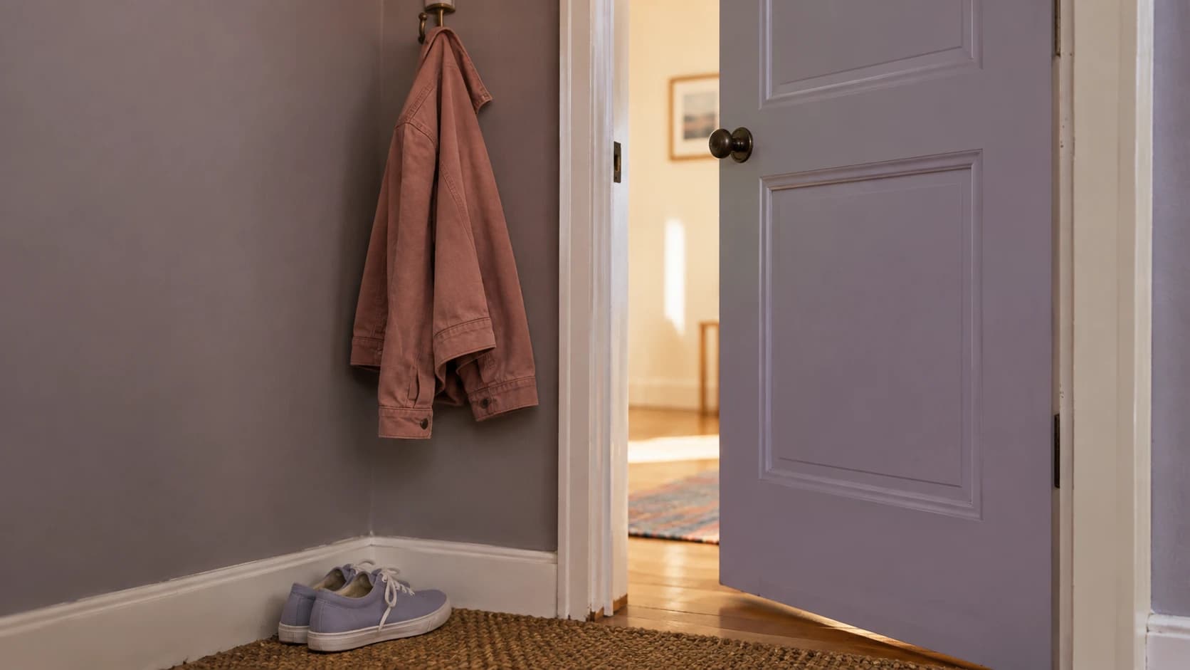 A lilac door left open, with a rose jacket hanging beside it.